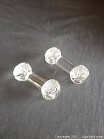 Pair of crystal barbell knife rests shown on a dark cloth background, capturing overall shape and form.