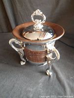 Silver-toned vintage ice bucket with ornate seahorse handles, removable lid, and textured brown midsection