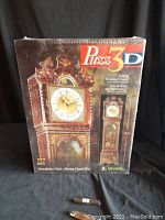 Front view of sealed 3D puzzle box showing assembled grandfather clock and branding information.
