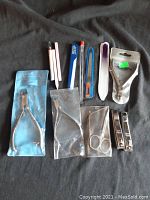 Full view of all nail care tools laid out on black fabric, showing metal clippers, scissors and multiple files.