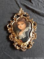 Overall photo of ornate gold wooden frame holding girl's portrait