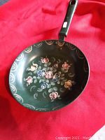 View of the entire pan showing decorative floral painting inside the pan and scalloped edge.