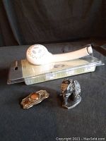 Photo showing all three items together: new shower head still in packaging, soap stone elephant figurine, and pants buckle with brown stone