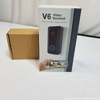 Photo of packaged V6 Video Doorbell box displaying image of doorbell, branding, and key features such as WiFi, HD video, and weather resistance.