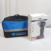 Blue and black soft case labeled 'Roadside Emergency Kit' with boxed air compressor next to it