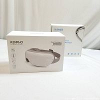 Photo of boxed Renpho eye massager and Homiee neck massager boxes side by side on white surface.
