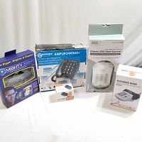 Photo of all five devices in their boxes: the multifunction telephone, LED magnifying eyewear, electronic blood pressure monitor, pulse oximeter, and elderly SOS alert system.