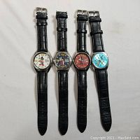 All four watches laid flat side by side showing full straps and cases