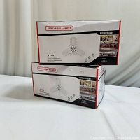 Two unopened boxes of Garage Light retrofit LED garage lights, each box containing 2 lights.