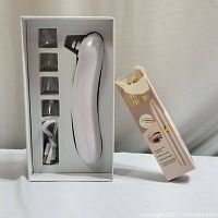 White blackhead suction device with multiple suction heads and USB charging cable in white packaging.