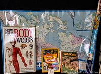 Photo showing all five items: How Your Body Works anatomy book, Wild Cats book, Bet You Didn't Know! fact book, and two maps (Canada and world) spread out.