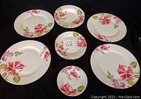 Photo showing all items in the floral dish set arranged on a dark background. Includes larger plates, side plates, bowls, and dessert plates with consistent floral pattern.