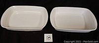 Two rectangular white ceramic CorningWare baking dishes side by side on black cloth showing overall shape and size.
