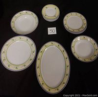 Photo showing entire dish set: six 6-inch plates, six 8-inch plates, one 10.5-inch plate, one 10 by 14-inch oval platter, and two bowls, each with a calla lily floral border on white ceramic.