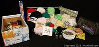 Wide view of all sewing supplies including yarn balls, pins, needles, thimbles, and buttons.