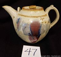 Front profile of ceramic teapot showing decorative painted splashes and overall shape.