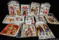 Full assortment of circa 15 assorted children's and one woman's sewing patterns, packaged, showing various clothing designs and brands.