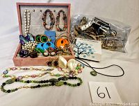 Photo showing the entire collection of costume jewelry laid out, including necklaces, earrings, and bracelets with a bag of extra small items in the background.