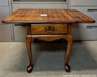 Front view of wooden folding table showing drawer and cabriole legs.
