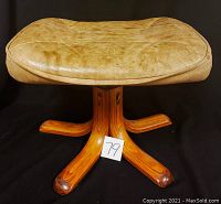 Angled view of the padded leather and wood stool showing seat and wooden legs