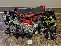 Eight pairs of child/youth hockey skates in black with white and yellow laces, arranged in two rows showing used condition.