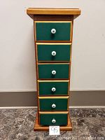 Front view of six-drawer stand showing natural wood frame and green drawer fronts