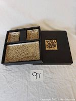 Photo showing the sushi set in original black box with lid displaying gold Japanese logo.