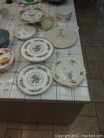 Full display of assorted cake platters and servingware showing floral patterns, covered dishes, and decorative bowls.