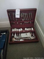 Wooden box open showing sterling flatware in top and bottom compartments