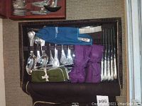 Full view of roll-up silverplate cutlery case with pouches open showing knives, spoons, forks, crumb brush and pan