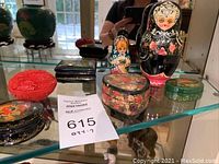 Photo showing two Russian babushka dolls, red carved box, heart-shaped floral box, small green box, and rectangular decorative box.