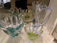 Photo showing all three colorful crystal flower bowls with green and blue accents, displayed on a reflective surface in front of a mirror.