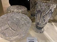 Crystal glass bowl and vase together on a reflective surface showing detail and design.