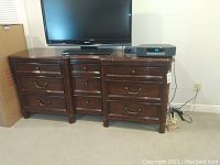 Front view of the dark brown wooden dresser with nine drawers and a television on top