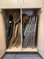 Photo showing multiple folded chairs inside a cabinet, including two wooden Stakmore folding chairs, five Samsonite metal framed folding chairs, two black fabric folding chairs, one brown folding chair.