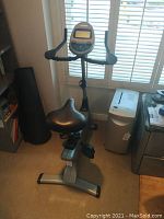Vision Fitness exercise bike positioned near a window, showing seat, pedals, and handlebars with digital display.