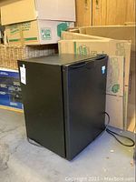 Black Avanti mini fridge, side view with power cord visible