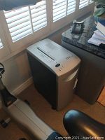 Full view of Fellowes Powerhouse C-14 shredder in a room near window and chair.