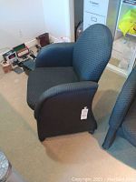 Front-angle view of the black fabric office chair, highlighting the seat and armrests.