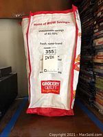 Photo of a Grocery Outlet bag labeled 'DVDs' containing multiple DVDs and sleeves.