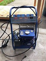 Front view of the blue gas pressure washer showing the motor and hose setup.