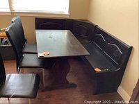 Wide shot of the corner bench, dining table, and three chairs showing general condition and wear.