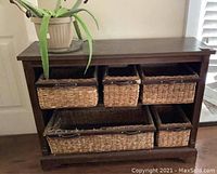 Front view of the wooden shelving unit with six wicker baskets, showing dark wood finish and baskets arranged in two rows.
