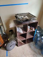 Wide view of wooden shelf unit with vases, amethyst, stones, and water containers nearby
