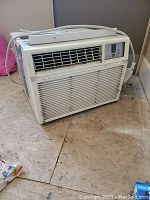 Image of white window air-conditioning unit showing front vents and control buttons