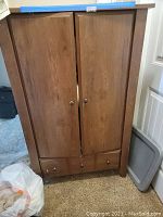 Wooden cabinet with closed doors showing wood grain and round metal knobs.