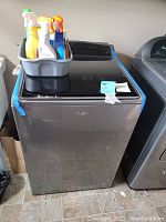Washer with cleaning supplies on top in room.