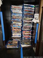 Photo showing large stacked collection of DVDs and Blu-Rays in cases inside a shelf.