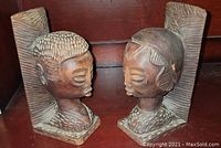Front-facing view of carved wooden African man and woman bookends showing detailed facial features and hair textures.