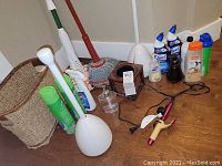 Cleaning supplies, curling iron, shells and household items arranged on wood floor